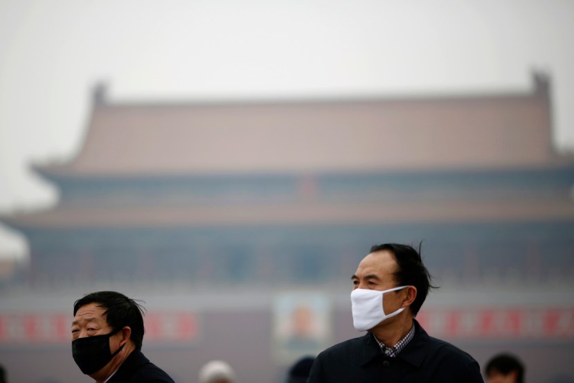 People wearing masks are seen on a hazy day at Tiananmen Square in Beijing