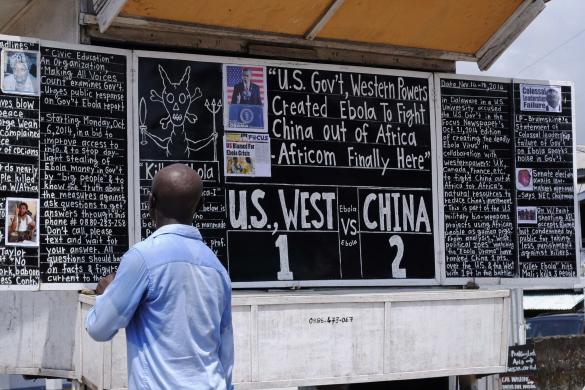 A man reads a board extolling China's contribution to the fight against Ebola, in Monrovia