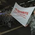 Members of a medical aid team of People’s Liberation Army (PLA) carry a flag during their departure ceremony at Beijing Capital International Airport, in Beijing